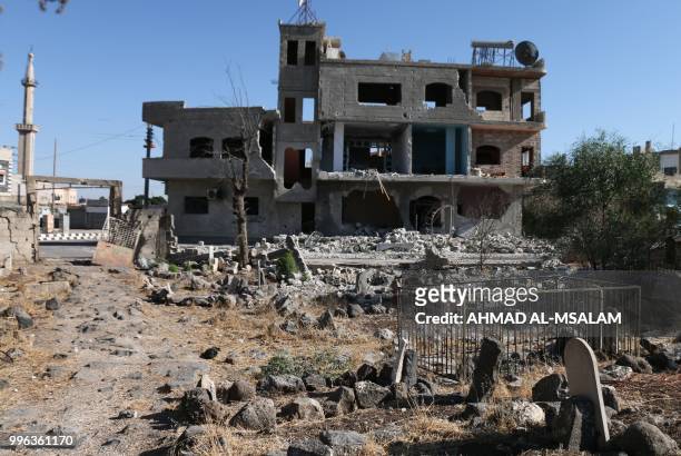This general view taken on July 11 shows makeshift graves in front of buildings destroyed during airstrikes by Syrian regime forces in the rebel-held...