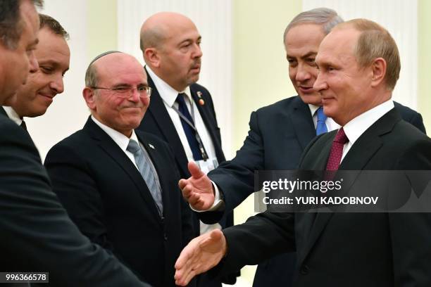 Russian President Vladimir Putin shakes hands with members of Israeli delegation next to Israeli Prime Minister Benjamin Netanyahu during their...