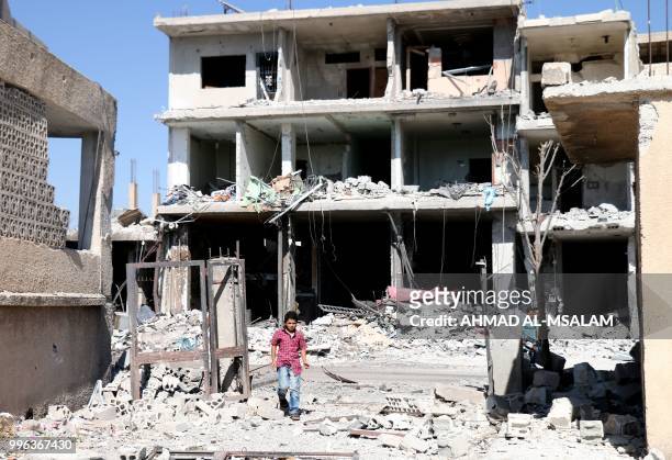Young boy walks among buildings destroyed during airstrikes by Syrian regime forces in the rebel-held town of Nawa, about 30 kilometres north of...