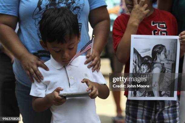 Boy plays on his mobile phone as protesters rally against the separation of immigrant families in front of a U.S. Federal court on July 11, 2018 in...