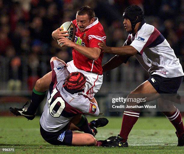 Centre Rob Henderson of the British Lions is tackled by fly half Elton Flatley and number eight Toutai Kefu of the Queensland Reds during the match...