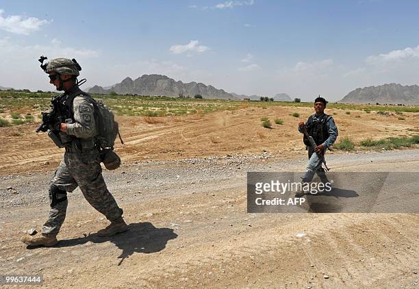 Soldier from Bravo Troop 1-71 CAV and an Afghan National Police serviceman patrol in Belanday village, Dand district in Kandahar on May 17, 2010....