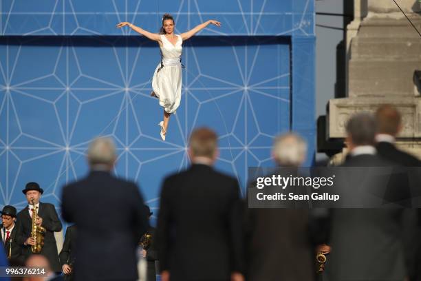 Performer dances suspended from balloons as heads of state and governments, as well as their spouses, watch at the evening reception and dinner at...