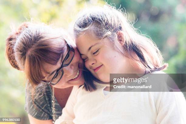 portrait of a mother with her daughter of 12 years old with autism and down syndrome in daily lives - special needs children stock pictures, royalty-free photos & images