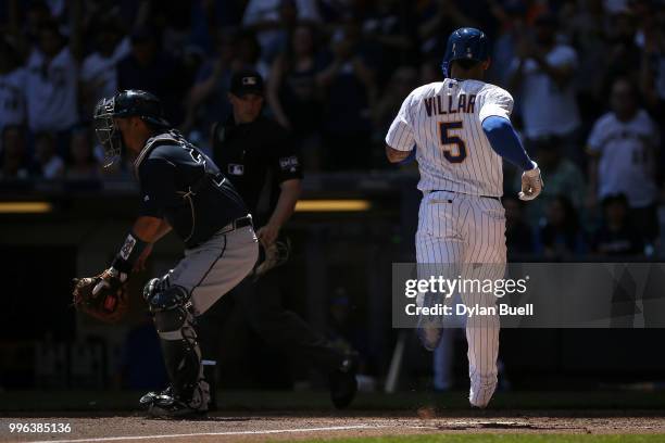 Jonathan Villar of the Milwaukee Brewers scores a run past Kurt Suzuki of the Atlanta Braves in the third inning at Miller Park on July 8, 2018 in...