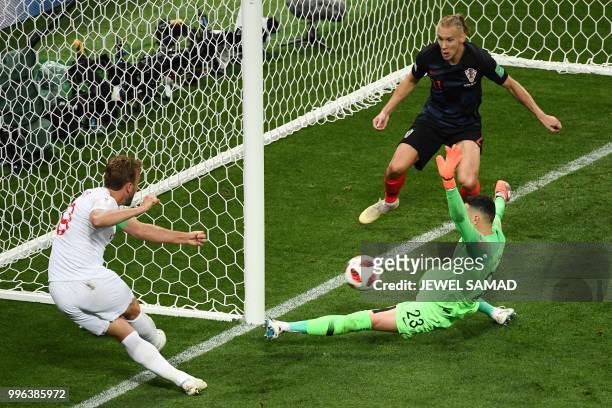 England's forward Harry Kane kicks the ball as Croatia's goalkeeper Danijel Subasic and Croatia's defender Domagoj Vida go to block it during the...