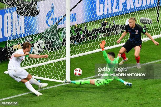 England's forward Harry Kane kicks the ball as Croatia's goalkeeper Danijel Subasic and Croatia's defender Domagoj Vida go to block it during the...