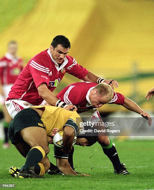 Martin Johnson and Neil Back of the British and Irish Lions combine to tackle Toutai Kefu of Australia during the third and final Test Match played...