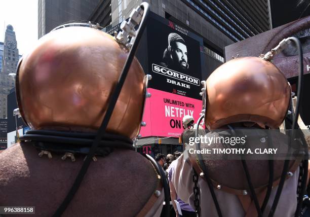 People with for the event in deep-sea diver outfits stand by as the work of artist Mel Chin, "Wake" and "Unmoored, is unveiled on Times Square July...