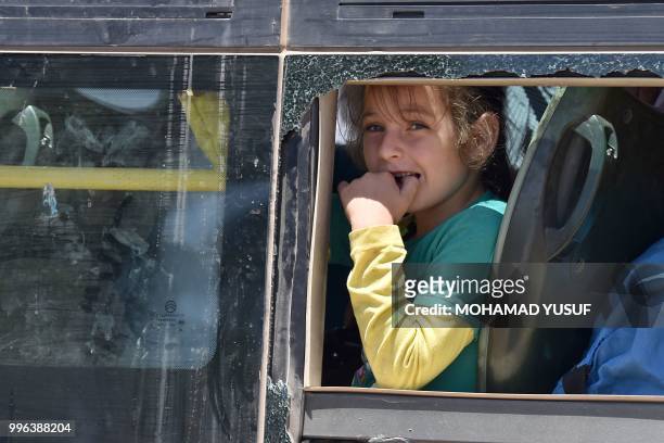 Child looks on in a bus as displaced Syrians from the Daraa province come back to their hometown in Bosra, southwestern Syria, on July 11, 2018. -...