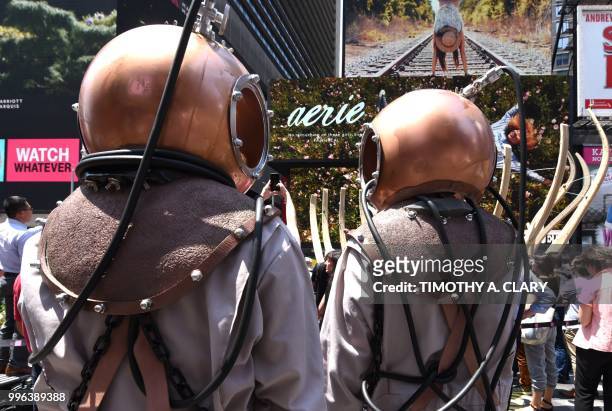 People with for the event in deep-sea diver outfits stand by as the work of artist Mel Chin, "Wake" and "Unmoored, is unveiled on Times Square July...