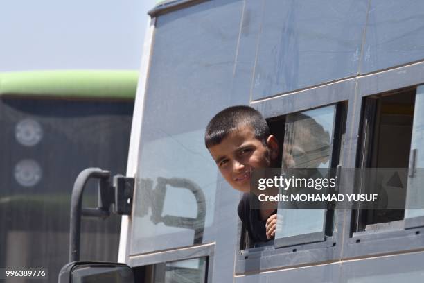 Child looks on in a bus as displaced Syrians from the Daraa province come back to their hometown in Bosra, southwestern Syria, on July 11, 2018. -...