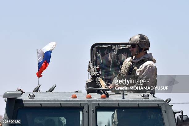 Russian soldier guards a checkpoint as displaced Syrians from the Daraa province come back to their hometown in Bosra, southwestern Syria, on July...