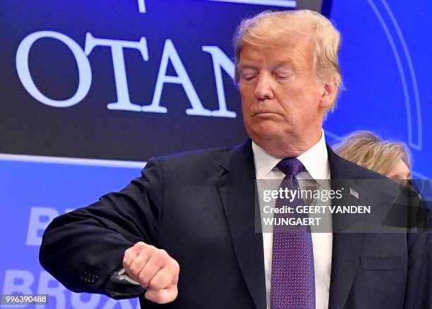 President Donald Trump checks time prior to a dinner of leaders at the Art and History Museum at the Park Cinquantenaire in Brussels on July 11,...