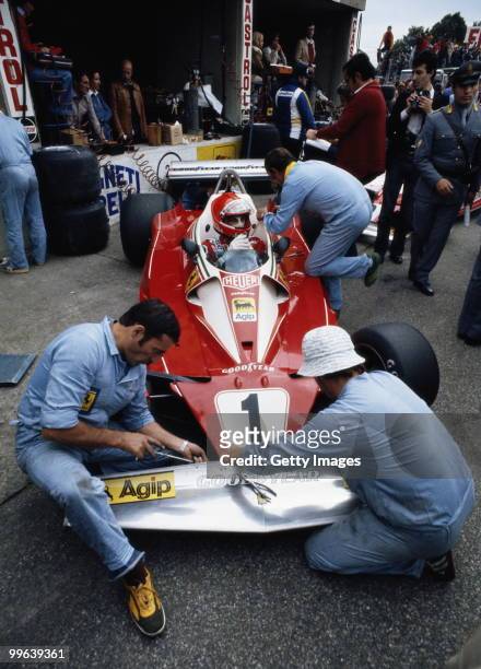 Niki Lauda sits aboard the Scuderia Ferrari 312T2 as mechanics make adjustments to the front wing before the Italian Grand Prix on 12 September 1976...