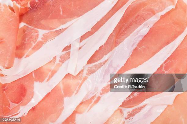 slices of italian ham prosciutto crudo close-up - crudo stock-fotos und bilder