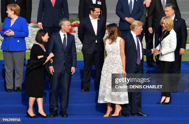 First Lady Melania Trump speaks with NATO Secretary General's wife Ingrid Schulerud and NATO Secretary General Jens Stoltenberg while holding hands...