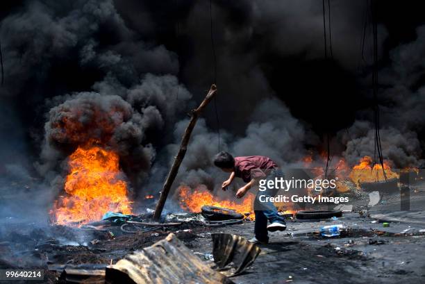 Thai anti-government red shirt protester throws wood onto a fire on a major Bangkok street as clashes continued on May 17, 2010 in Bangkok, Thailand....