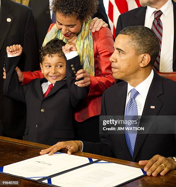 Mariane Pearl holds up Adam Daniel Pearl's arms after US President Barack Obama signed the Freedom of the Press Act in the Oval Office of the White...