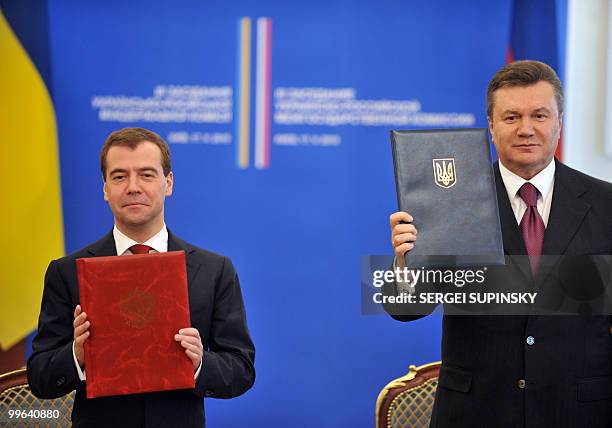 Ukrainie's President Viktor Yanukovych and his Russian counterpart Dmitry Medvedev hold up folders after signing documents in Kiev on May 17, 2010....