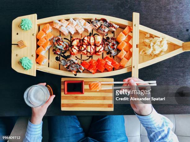 man eating sushi from a sushi boat in japanese restaurant, directly above personal perspective view - tokyo food stock pictures, royalty-free photos & images