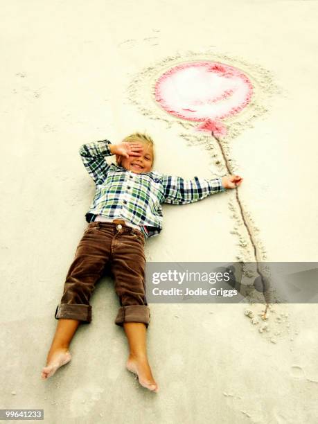 child holding balloon drawn in sand - swansea australia stock pictures, royalty-free photos & images
