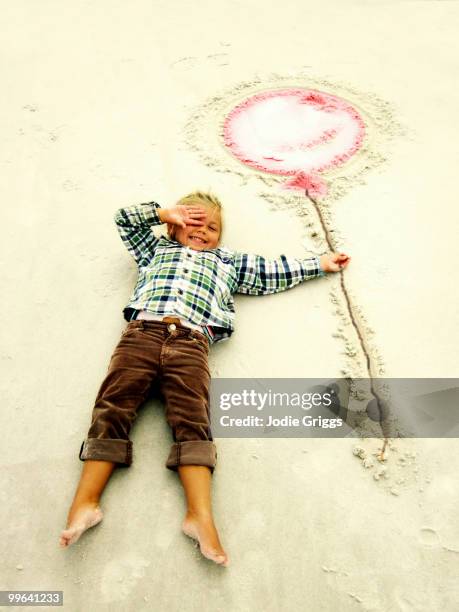 child holding balloon drawn in sand - west glamorgan stock pictures, royalty-free photos & images