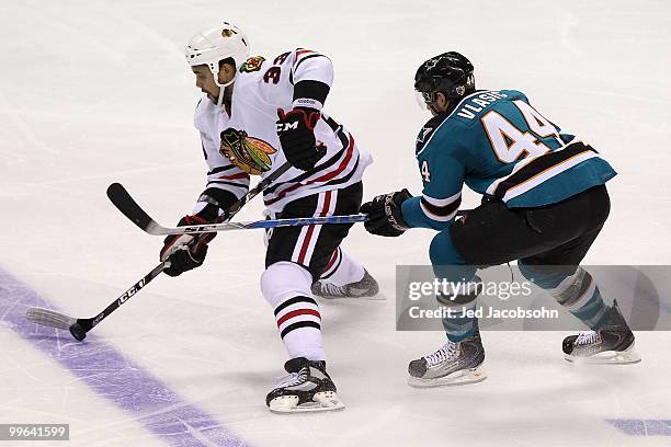 Dustin Byfuglien of the Chicago Blackhawks moves the puck in front of Marc-Edouard Vlasic of the San Jose Sharks in Game One of the Western...