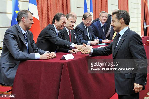 French President Nicolas Sarkozy shakes hands with French Leclerc hypermarket chain president Michel-Edouard Leclerc beside Intermarche hypermarket...