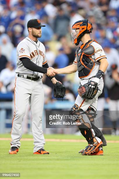 Hunter Strickland and Buster Posey of the San Francisco Giants shake hands after winning the game against the Los Angeles Dodgers at Dodger Stadium...