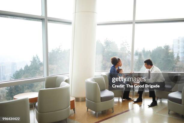 doctor talking with female patient in waiting room - mum sitting down with baby stockfoto's en -beelden