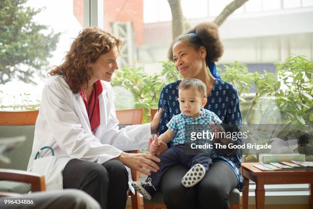 doctor talking with mother and baby in waiting room - family pediatrician stock pictures, royalty-free photos & images