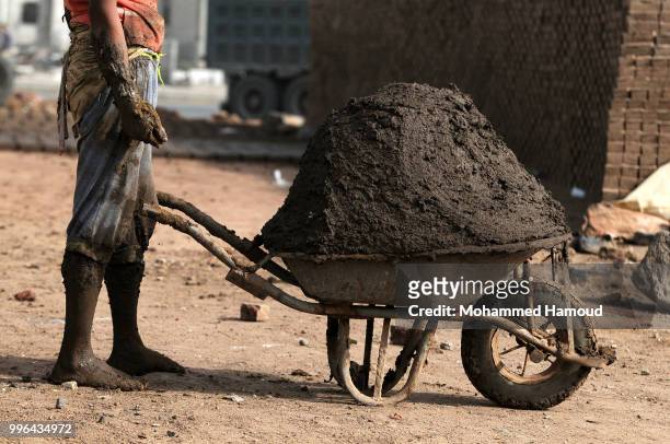 Worker prepares mud to make bricks at a mud bricks factory on July 07, 2018 in north Sana’a, Yemen. A mudbrick or mud-brick is a brick which dates...
