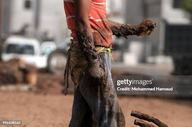 Worker prepares mud to make bricks at a mud bricks factory on July 07, 2018 in north Sana’a, Yemen. A mudbrick or mud-brick is a brick which dates...