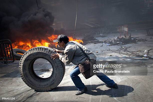 Red shirt protester runs past burning tires as the violence in central Bangkok continues May 17, 2010 in Bangkok, Thailand. So far in clashes over...