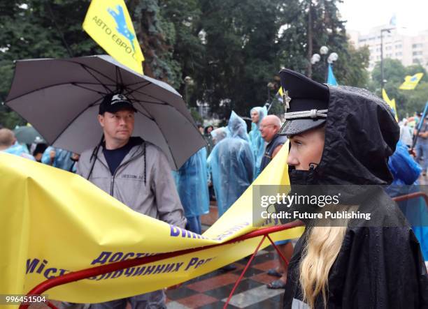 Police officer in a peaked cap covered with a hood stands guard during a rally for the adoption of a draft bill on customs clearance and lower tax...