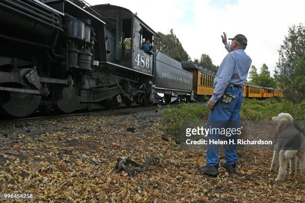 Cres Fleming, with his dog Stella, waves to the fireman driving the Durango & Silverton Train Locomotive 486 as it makes its way towards Durango on...