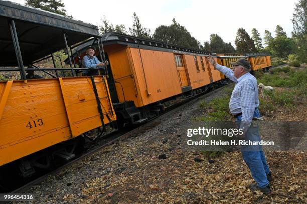 Cres Fleming, with his dog Stella, waves to conductor of the Durango & Silverton Train as it makes its way towards Durango on July 10, trains that...