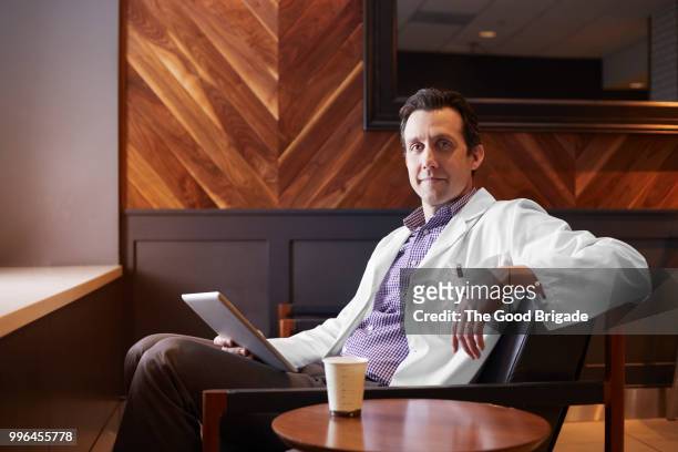 portrait of doctor sitting in hospital lounge - doctor sitting stock pictures, royalty-free photos & images