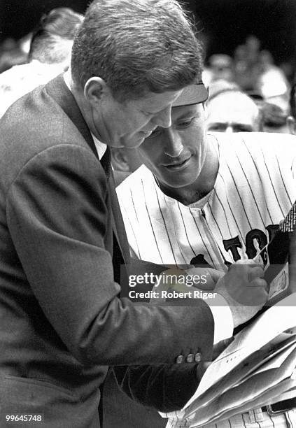 President John F. Kennedy signs an autograph for an unidentified Washington Senators player before the Opening Day game against the Detroit Tigers at...