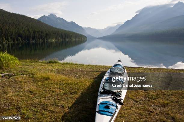 kayak resting on the shore of bowman lake at glacier national park, montana. - bowman lake stock pictures, royalty-free photos & images