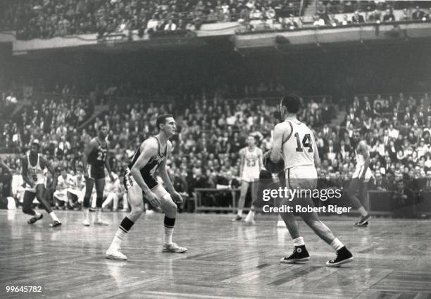 Bob Cousy of the Boston Celtics dribbles against Jerry West of the Los Angeles Lakers during a game in the 1962-63 season at the Boston Garden in...