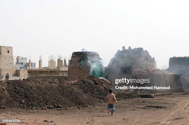 Boy walks near a kiln where bricks are fired at a mud bricks factory on July 07, 2018 in north Sana’a, Yemen. A mudbrick or mud-brick is a brick...