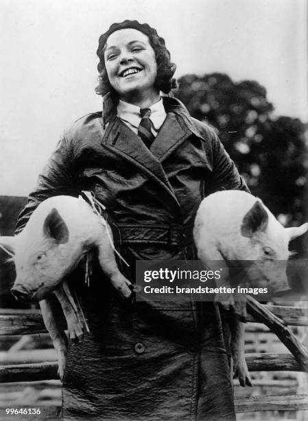 Woman with two pigs as a symbol of good luck for new years eve. Photograph. Around 1920/30.