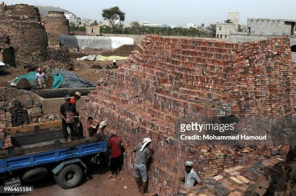 Workers load a truck with bricks at a mud bricks factory on July 07, 2018 in north Sana’a, Yemen. A mudbrick or mud-brick is a brick which dates back...