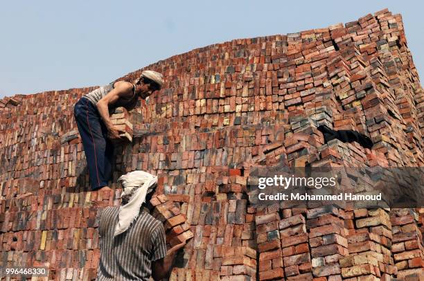 Workers arrange bricks for sale at a mud bricks factory on July 07, 2018 in north Sana’a, Yemen. A mudbrick or mud-brick is a brick which dates back...