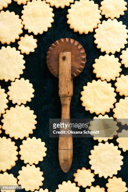 freshly baked butter cookies with old wooden cutter wheel. creative food concept. - idee stock pictures, royalty-free photos & images