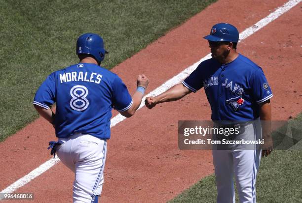 Kendrys Morales of the Toronto Blue Jays is congratulated by third base coach Luis Rivera after hitting a solo home run in the sixth inning during...