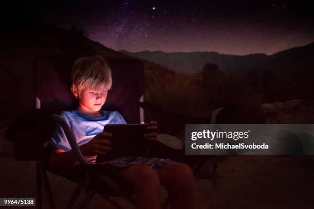 kleiner junge zonen heraus auf dem digitalen bildschirm - smartphone lesen nacht stock-fotos und bilder