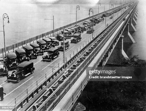 One third of a bridge across the Ottawa River has been rededicated to a parking lot. Photograph. Montreal, Canada. Around 1930.